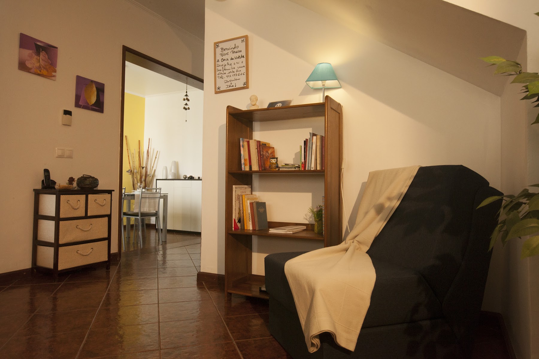 Reading nook with armchair, bookshelf, lamp, and plants